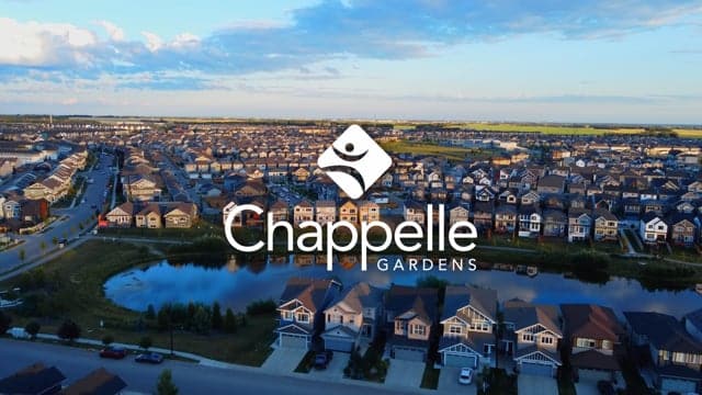 Aerial view of Chappelle Gardens residential community featuring lakes and modern homes under a partly cloudy sky.
