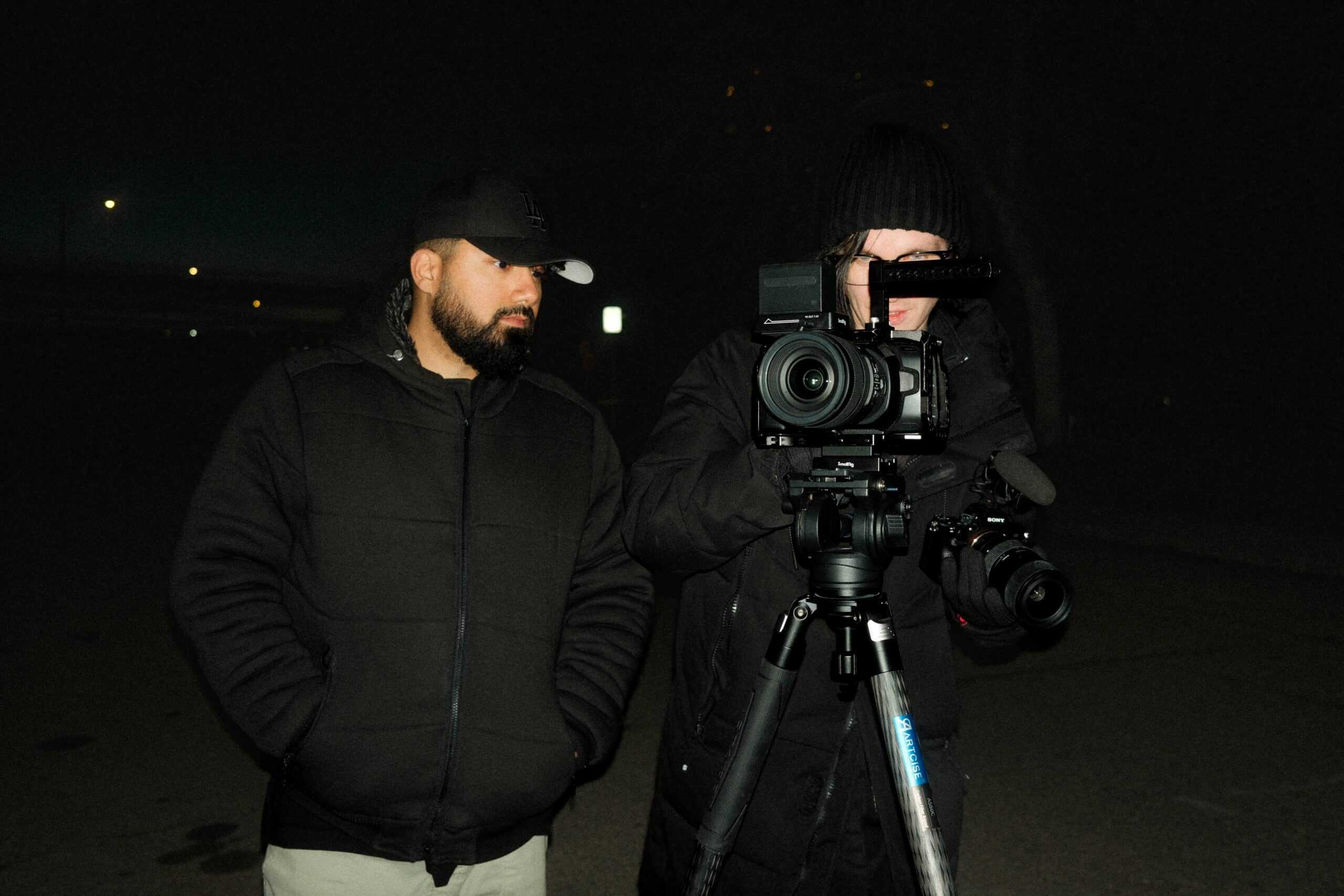 Behind-the-scenes filmmaker crew capturing video footage at night, professional camera equipment, dark urban setting, film production, video shoot, media production, cinematography, Q Filmz Media SEO content.
