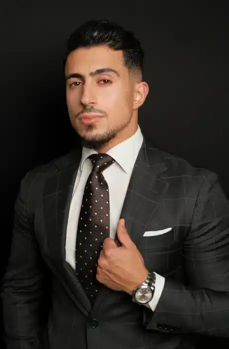 Sharp-dressed man in a black suit with a polka dot tie, posing confidently for a professional photo. Perfect for business and fashion-related imagery.