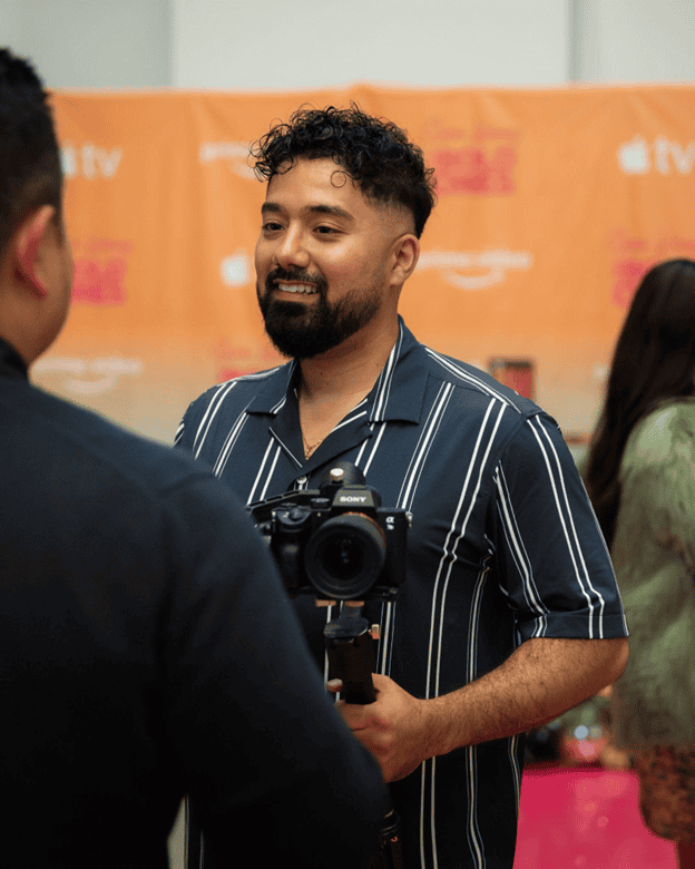 Young man with camera at Q Filmz media event, professional videography and filmmaking, creative industry, media production, event coverage.