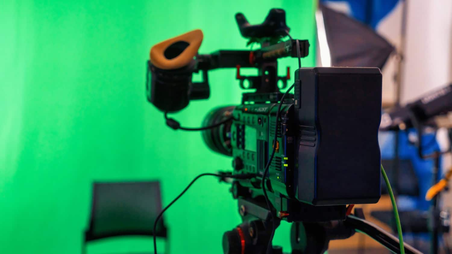 Professional camera setup on a film or video production set with a vibrant green screen background.