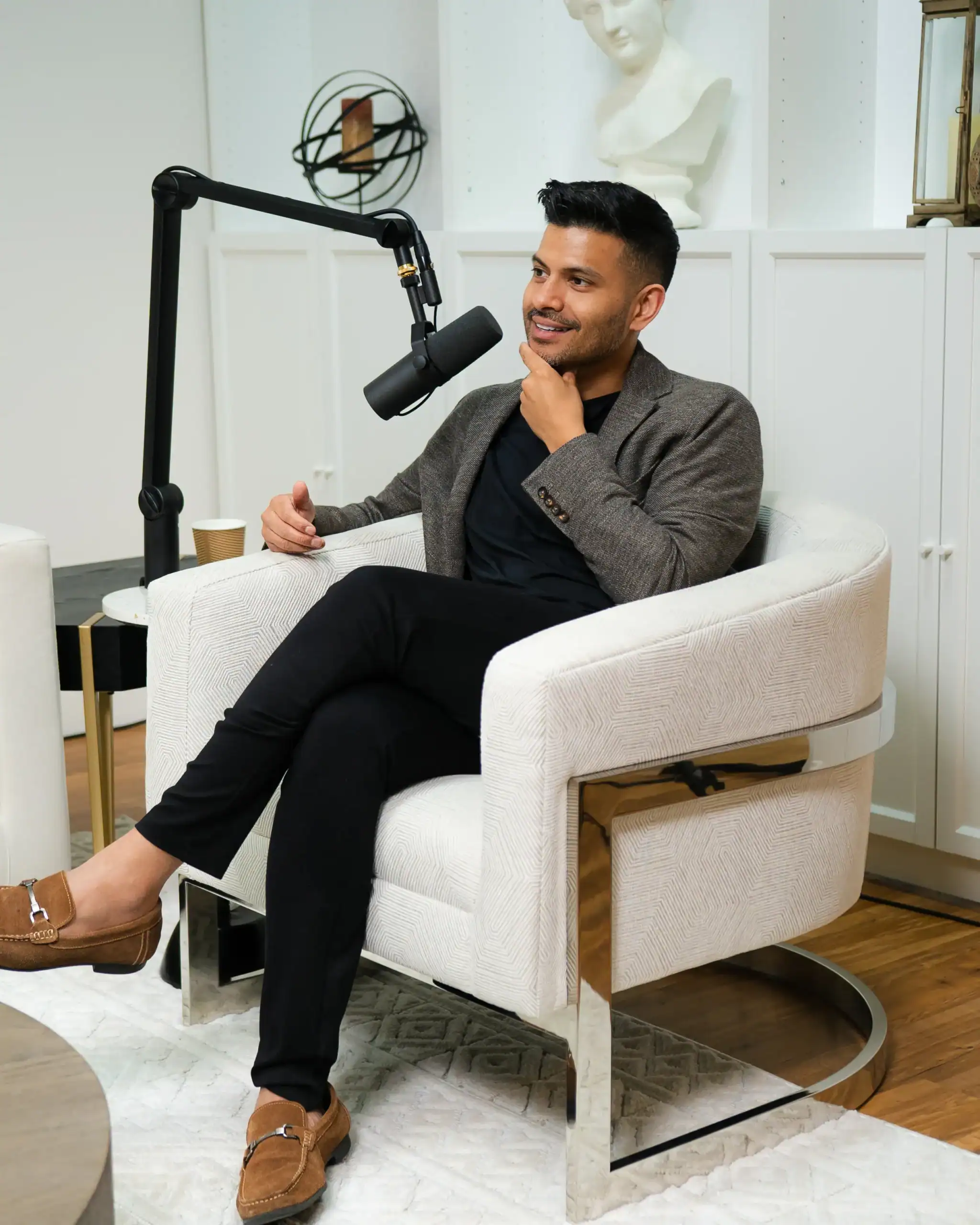 Professional man recording podcast or interview in modern studio setting with microphone and stylish decor.