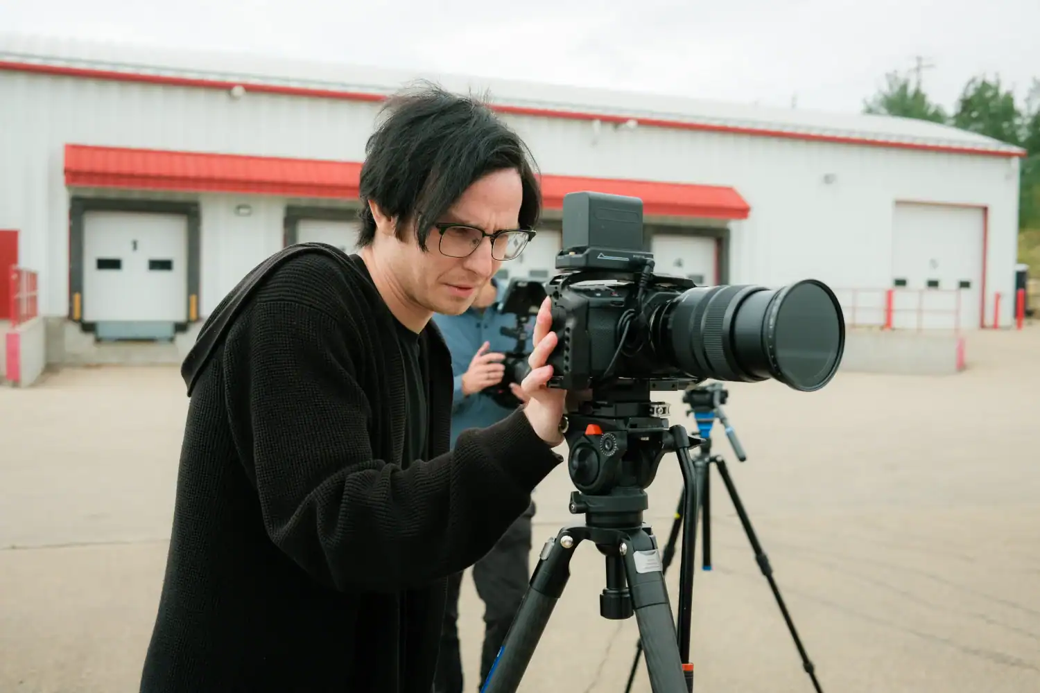 High-quality filmmaker operating a professional camera on set during outdoor shoot.