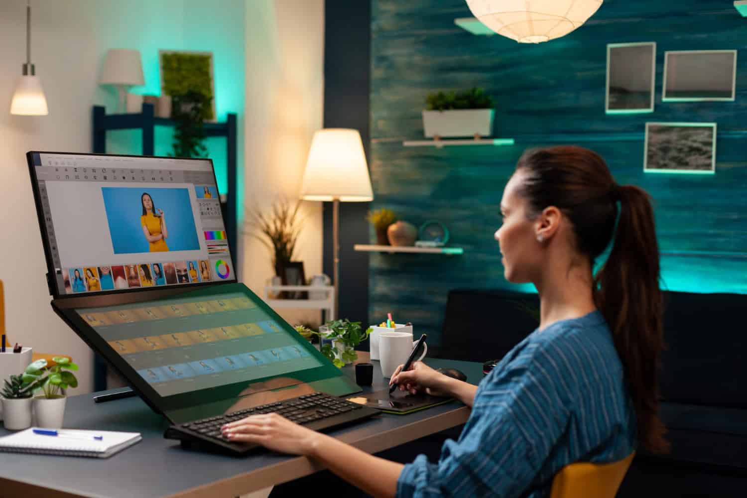 AlT text: Female graphic designer editing photos on dual-monitor setup in a modern, colorful workspace with creative lighting.