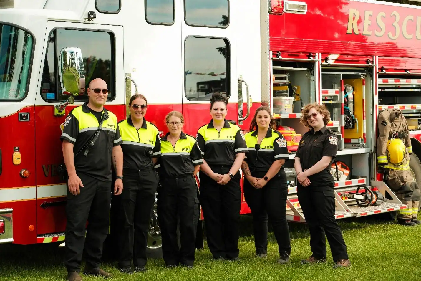 Bright fire rescue team standing in front of a red emergency fire truck, showcasing their firefighting gear and team spirit, ready for duty and community safety efforts.