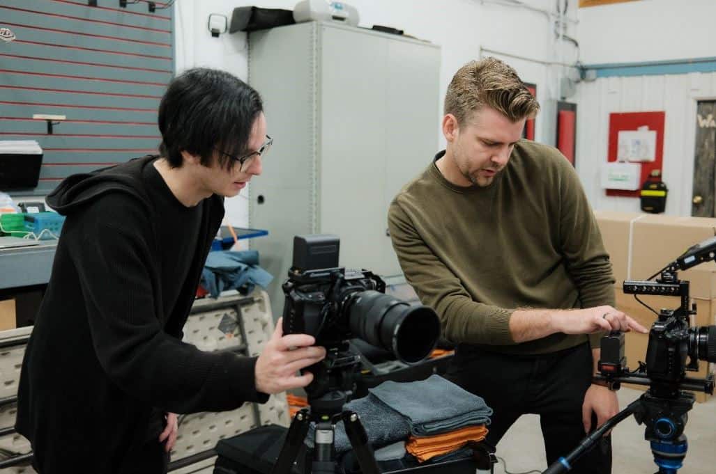 High-quality film production gear setup with two filmmakers adjusting camera equipment in a professional studio environment.