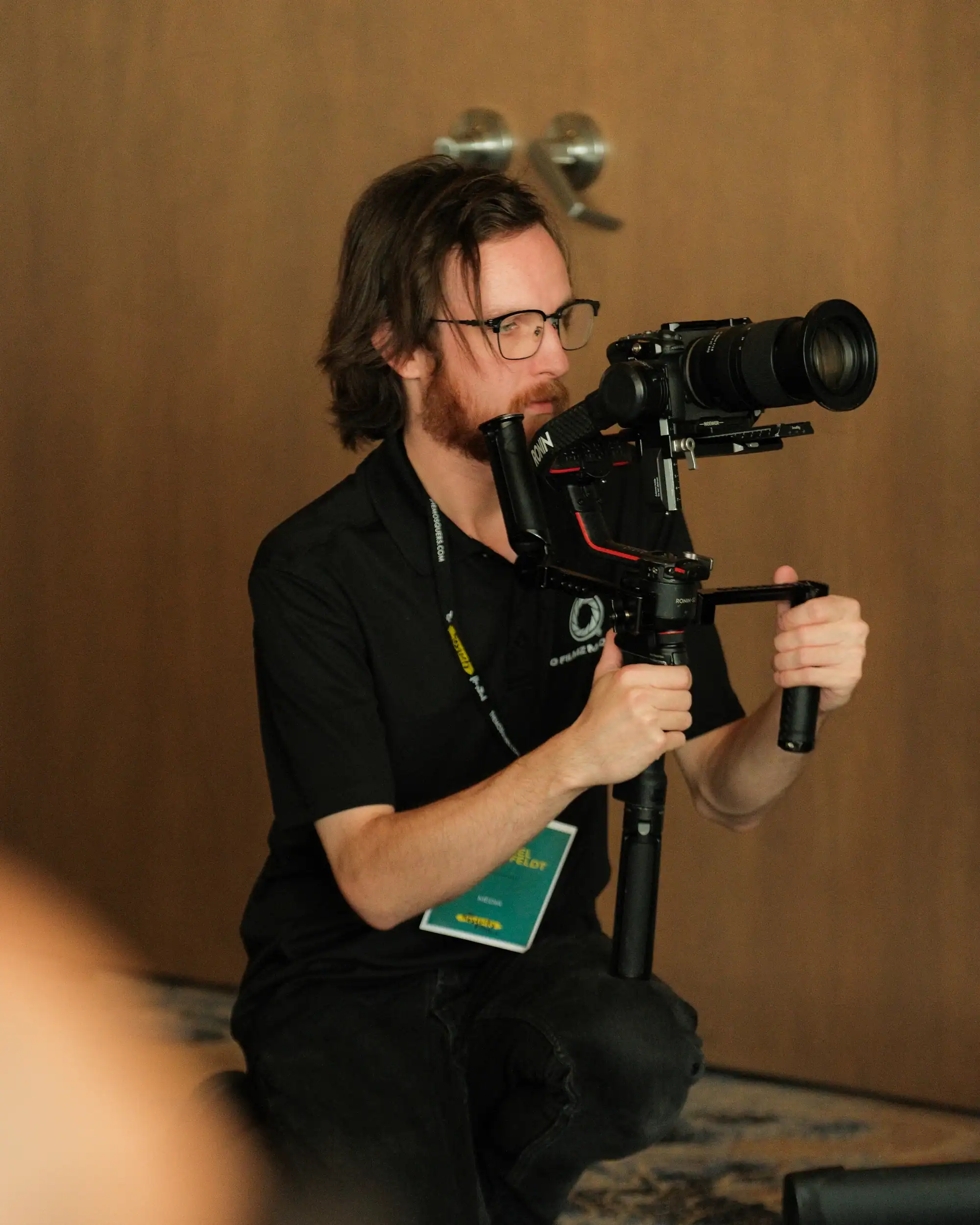 High-quality image of a professional videographer filming with a camera stabilizer rig at a media event. Focused on capturing cinematic footage, emphasizing videography, media production, and event coverage.