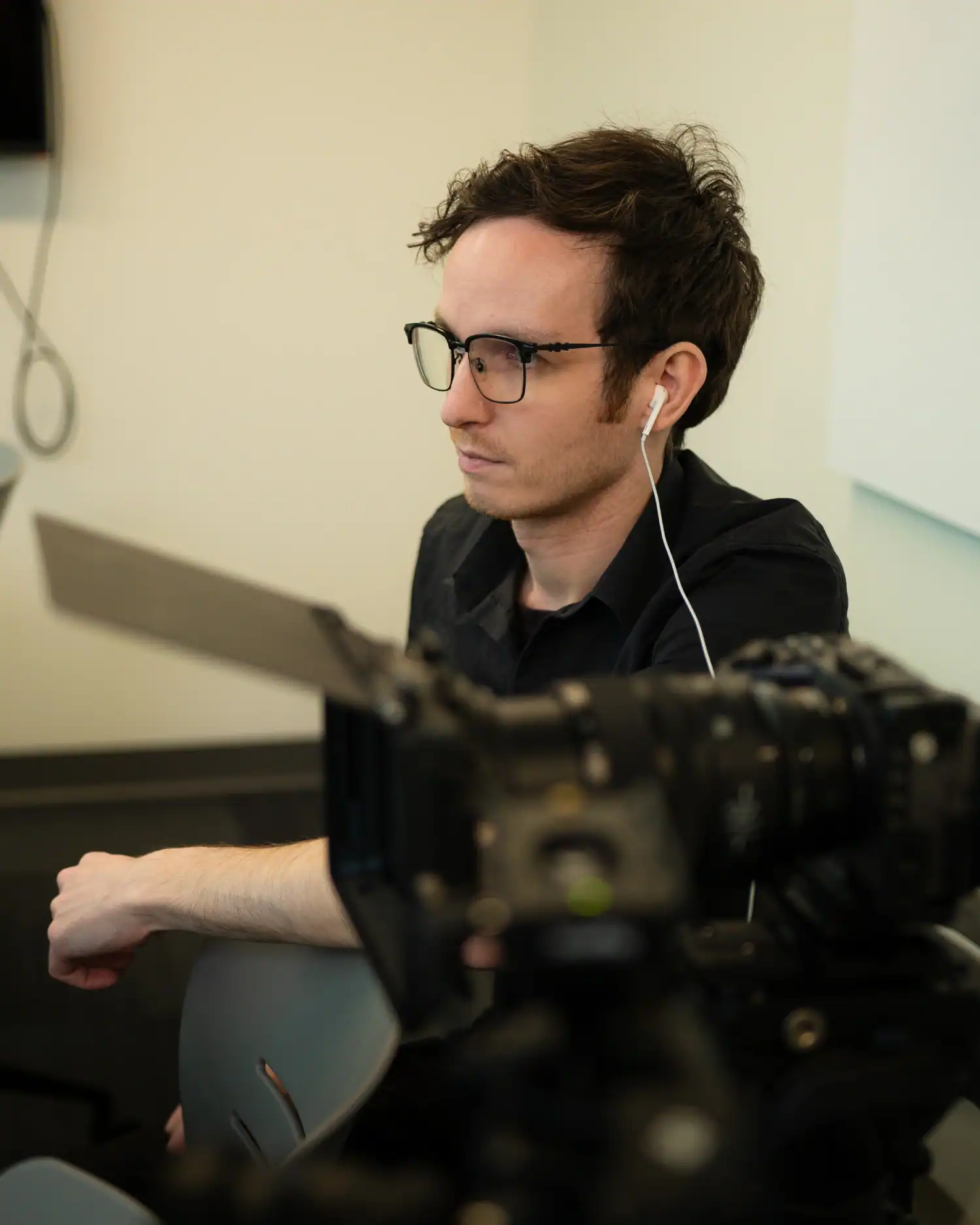 Professional videographer working with camera and headphones for filming or content creation at Q Filmz Media.