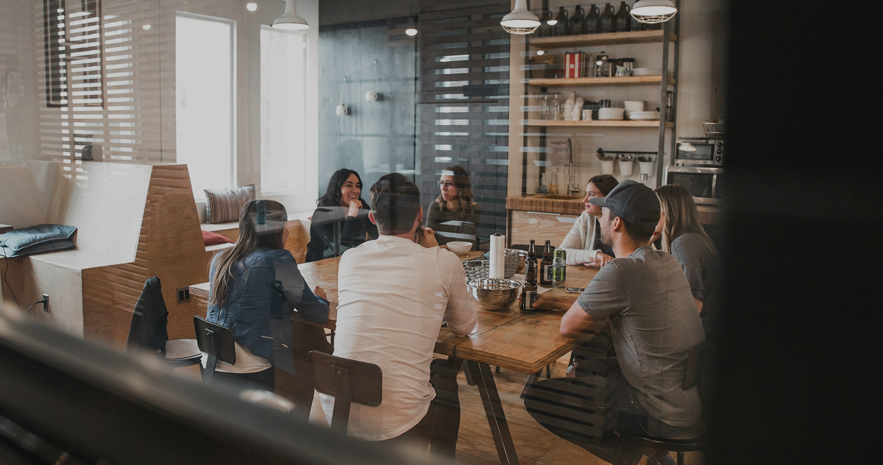 Group of diverse professionals having a business meeting in a contemporary office setting with wooden accents and natural light.