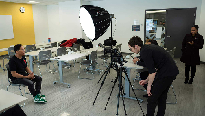 Behind the scenes of a corporate video shoot with professional lighting and camera equipment in a modern office space.