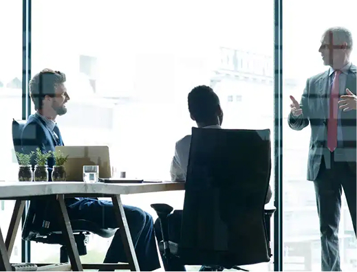 Business professionals having a discussion in a modern office with large windows and city view.