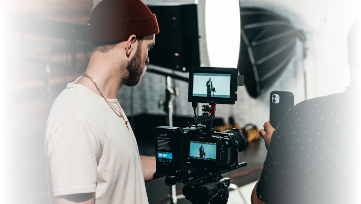 Filmmakers working on a professional video shoot with camera equipment in a studio setting.