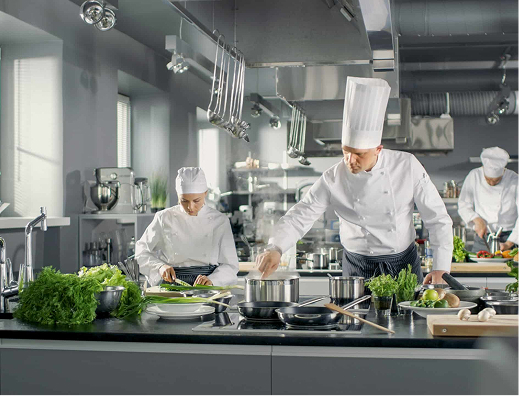 Team of professional chefs preparing dishes in a contemporary commercial kitchen with fresh ingredients and cooking utensils.
