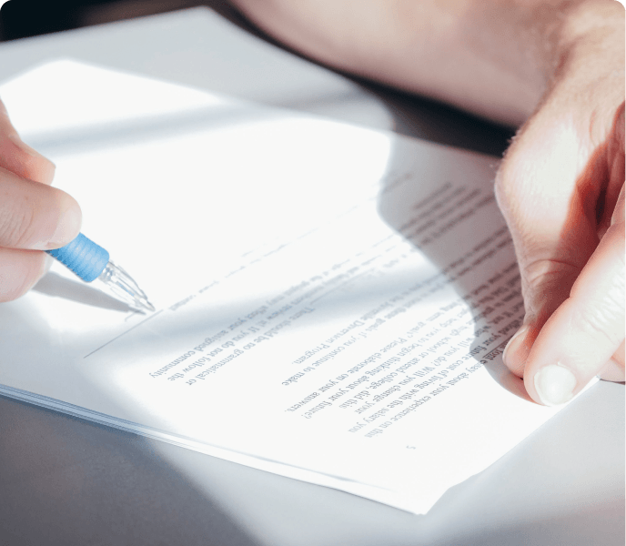 Close-up of a person signing a document with a blue pen, related to education or academic agreements.