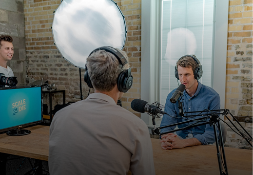 Professional podcast recording session with two hosts and a guest in a studio with lighting and audio equipment.