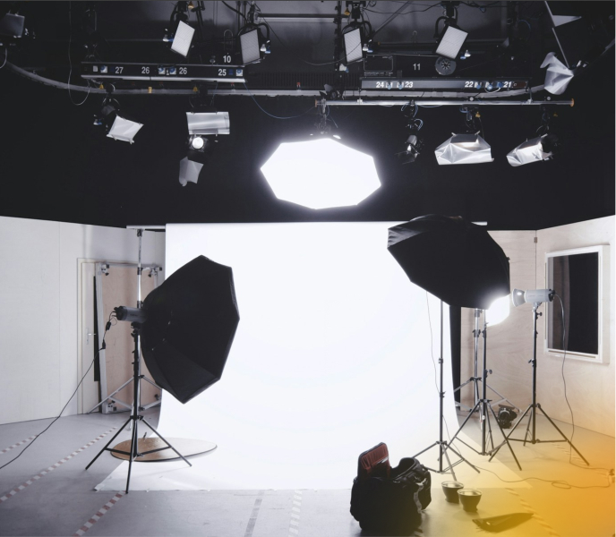 Inside a professional photography studio with lighting equipment, softboxes, and a white backdrop for high-quality video and photo production.