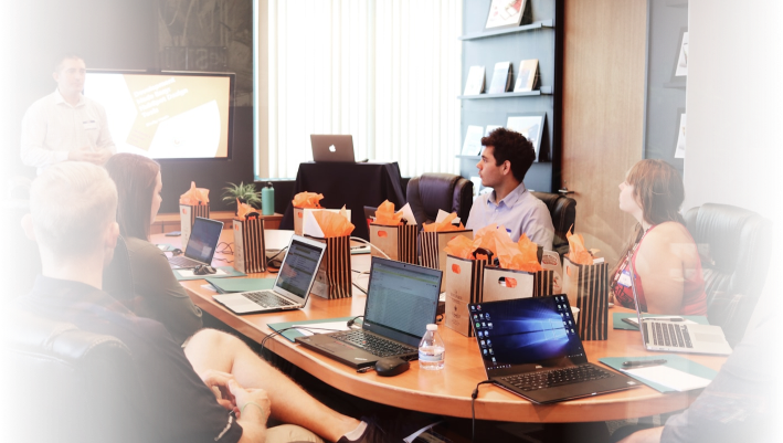 Team of professionals in a business meeting at Q Filmz Media, with laptops and presentation screen in a modern conference room.
