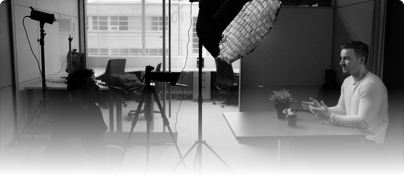 Behind the scenes of a media production with a camera operator and a presenter in a modern studio setting.