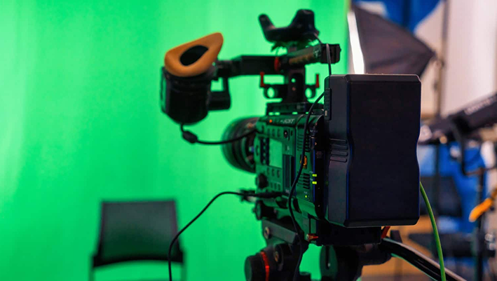 High-quality professional video camera with green screen background, used for corporate video production and media content creation.