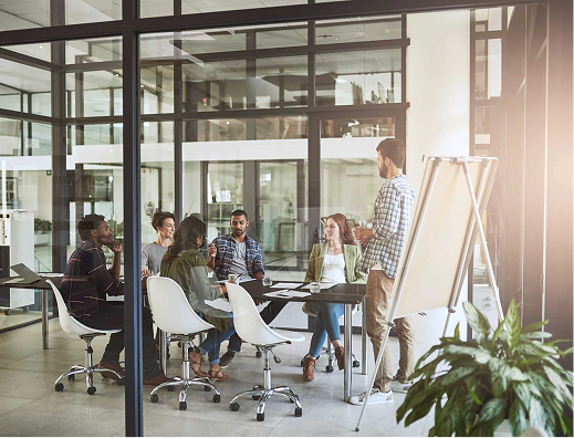 Team of professionals engaged in a business meeting in a contemporary office space with glass walls and natural lighting.