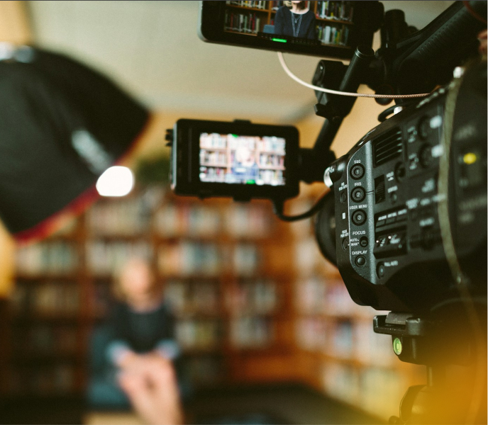 Professional video camera recording an interview or scene in a library setting for Q Filmz Media portfolio.