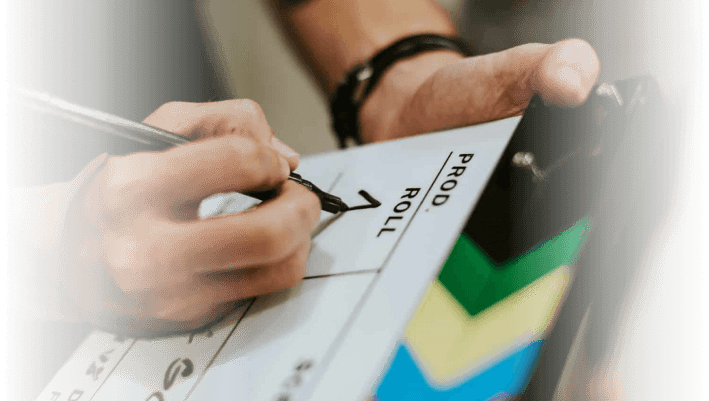 Close-up of a person signing a film slate with colorful markings, representing professional video production services in Edmonton.