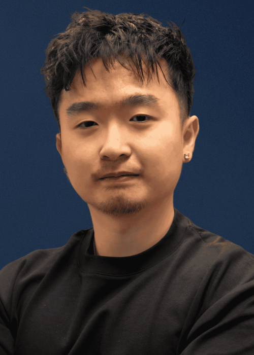 Young Asian man with short dark hair, beard, and earrings, wearing a black shirt against a blue background, representing modern cinephile or digital media influencer.